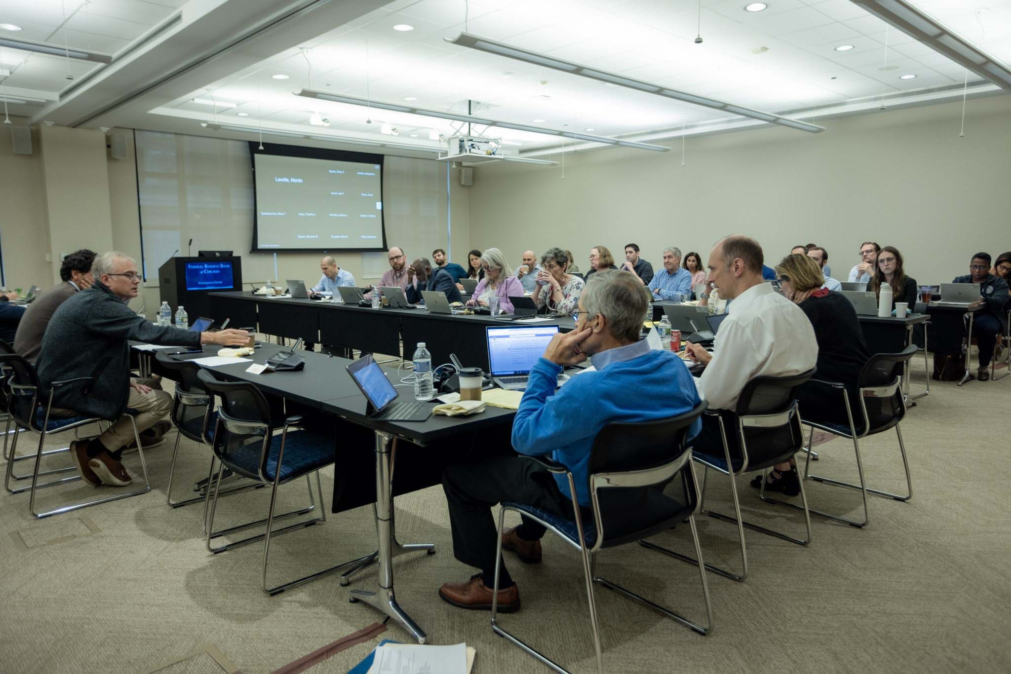 A large group of people seated around conference tables.